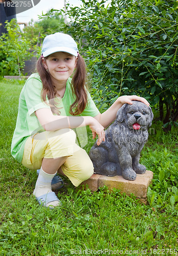 Image of Smiling little girl near to concrete dog