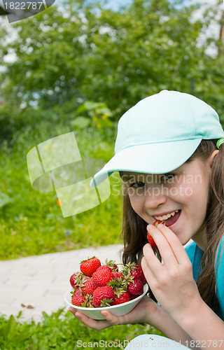 Image of Little girl eats ripe strawberry