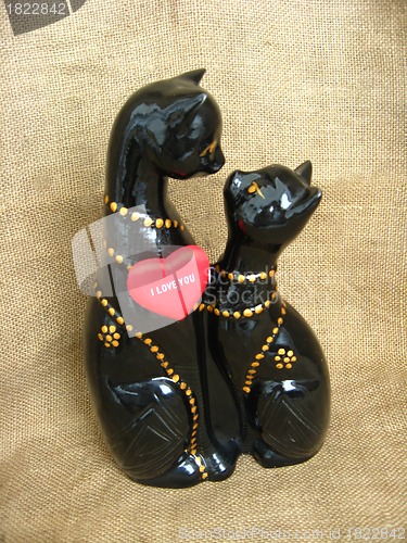 Image of Two toy enamoured cats on a brown background