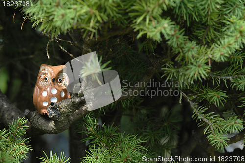 Image of ceramic owl on the branch of a fir tree