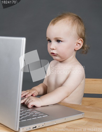 Image of baby with laptop computer in grey background