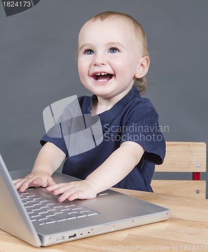 Image of baby with laptop computer in grey background