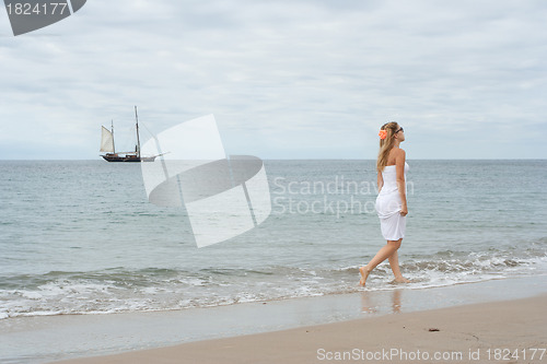 Image of Girl in white dress on the coast with old ship in the background