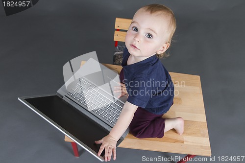 Image of baby with laptop computer in grey background