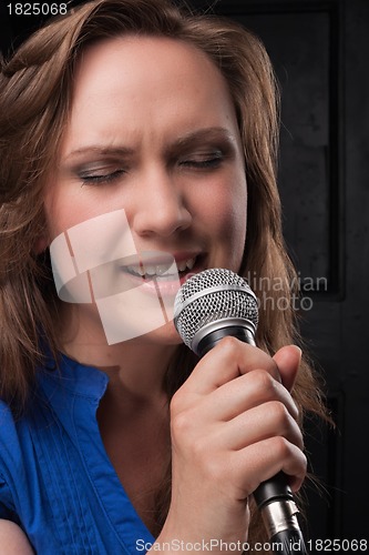 Image of Girl singing to the microphone in a studio