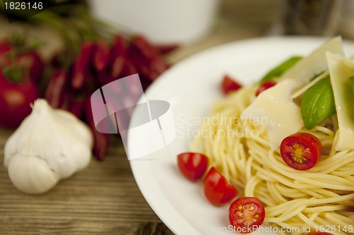 Image of fresh tasty pasta with tomato and basil on table