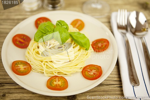 Image of fresh tasty pasta with tomato and basil on table