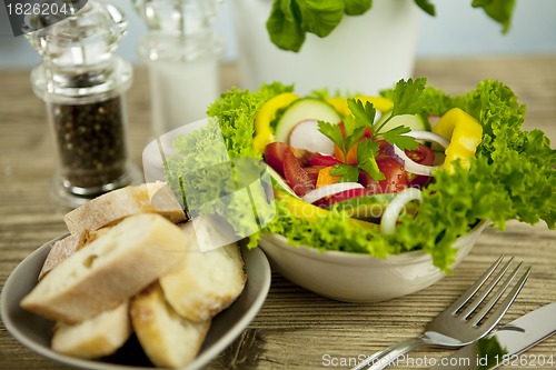 Image of fresh tasty healthy mixed salad and bread on table