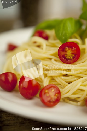 Image of fresh tasty pasta with tomato and basil on table