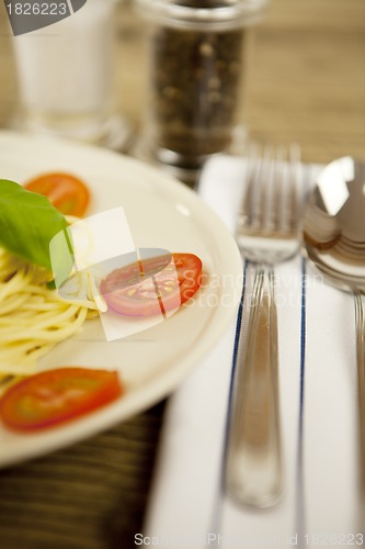 Image of fresh tasty pasta with tomato and basil on table