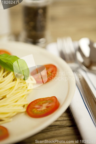 Image of fresh tasty pasta with tomato and basil on table