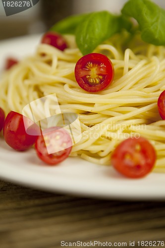 Image of fresh tasty pasta with tomato and basil on table