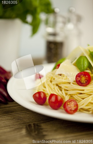 Image of fresh tasty pasta with tomato and basil on table