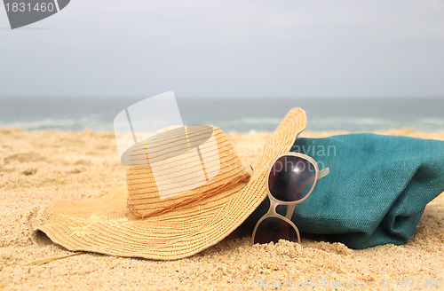 Image of  Blue beach bag on the seacoast and straw hat 