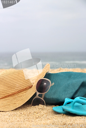 Image of  Blue beach bag on the seacoast and straw hat 