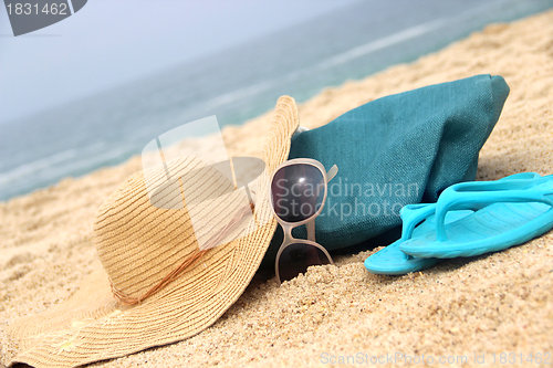 Image of Blue beach bag on the seacoast and straw hat 