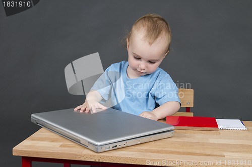 Image of baby with laptop computer in grey background