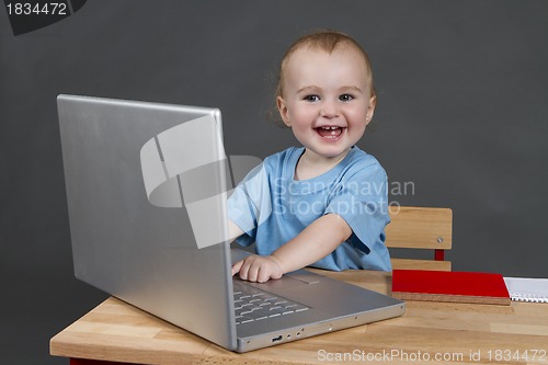 Image of baby with laptop computer in grey background