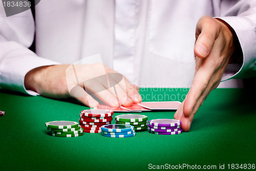 Image of men's hands, playing cards and chips