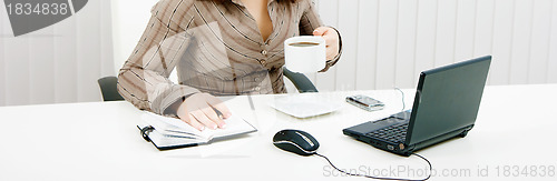 Image of woman drinking coffee at work with
