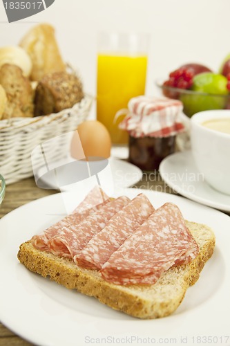Image of tasty breakfast with salami toast on table