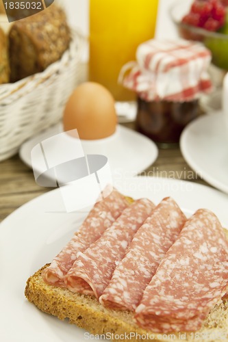 Image of tasty breakfast with salami toast on table