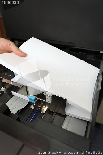 Image of details of hand inserts a paper A4 into a laser copier