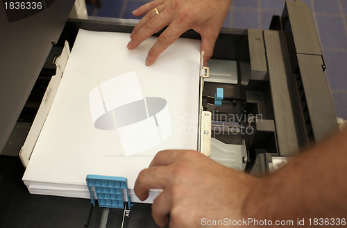 Image of details of hand inserts a paper A4 into a laser copier 