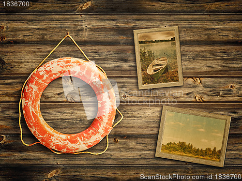 Image of lifebuoy and old travel photos at wooden background