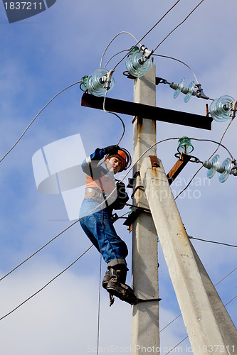 Image of Electrician connects wires on a pole