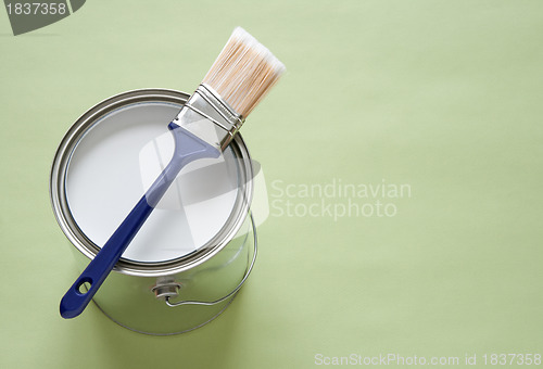 Image of Paintbrush and a can of white paint on green background