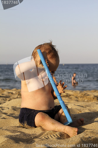 Image of Baby playing with toy on a sandy beach