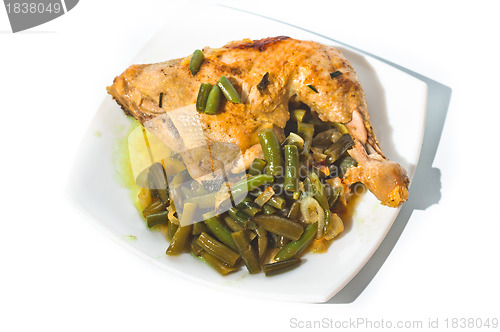 Image of Fried chicken leg with french beans on white plate.