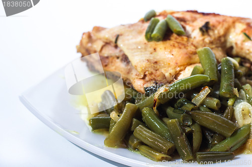 Image of Fried chicken leg with french beans on white plate.