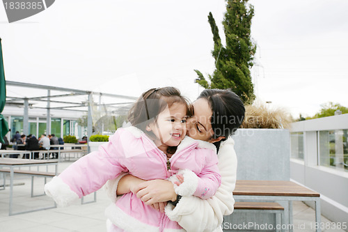 Image of Happy little girl receiving a kiss of her mother