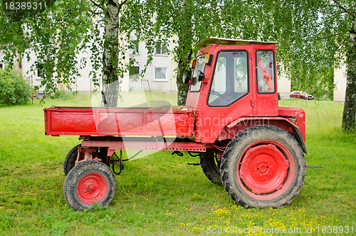 Image of Retro red agricultural tractor under birch trees 