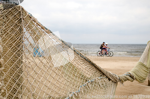 Image of Beach fence decorated net cyclists going near sea 
