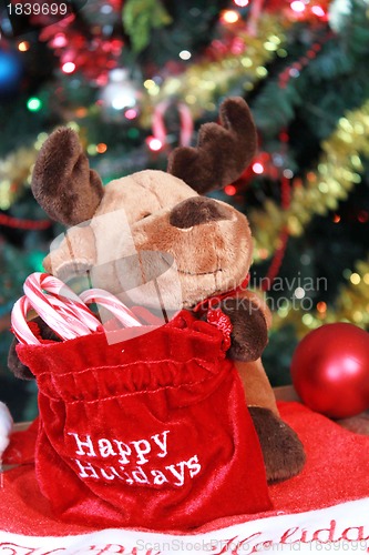 Image of Reindeer decoration with bag of candy canes under Chrstmas tree