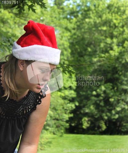 Image of Young woman wearing a Santa Hat with trees in  background