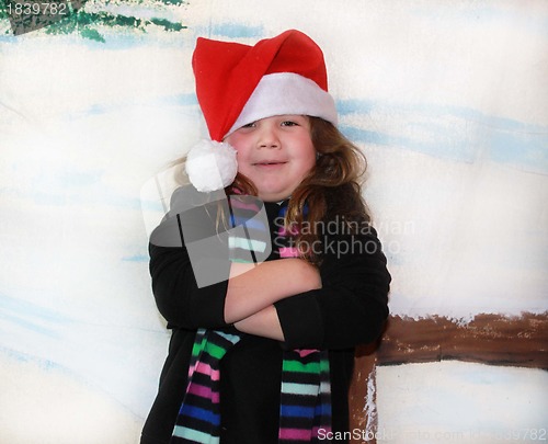 Image of Cute girl in snow wearing Santa hat