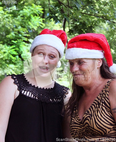 Image of Two women wearing Santa hats
