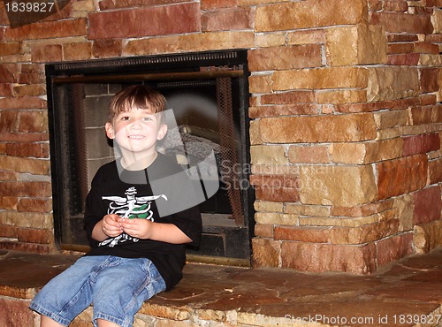 Image of Cute little boy sitting on fireplace