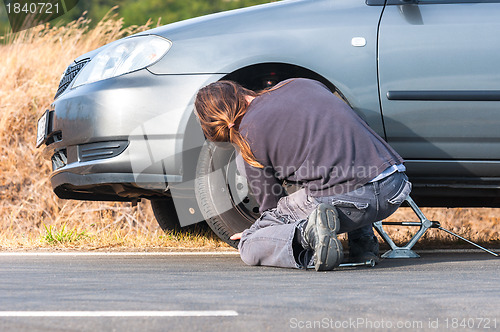 Image of Young man repairing car outdoors