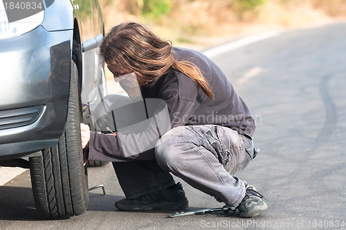 Image of Young man repairing car outdoors