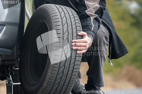 Image of Young man repairing car outdoors