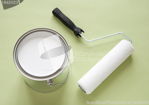 Image of Can of white paint and roller on green background