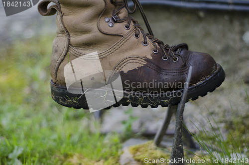 Image of A leather walking boot, being cleaned on an old cast iron boot s