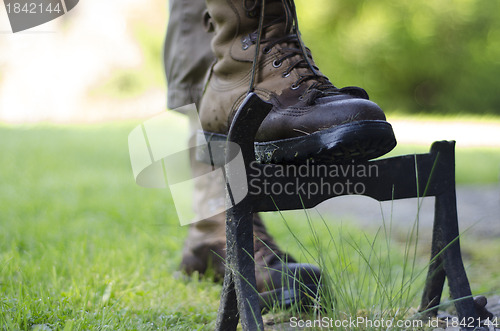 Image of A walker cleaning the soles  of walking boots on an old cast iro