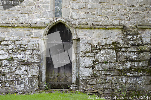 Image of An old wooden door, in the stone wall of an old 14th Century chu