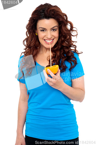 Image of Fit girl drinking fresh orange juice directly from fruit